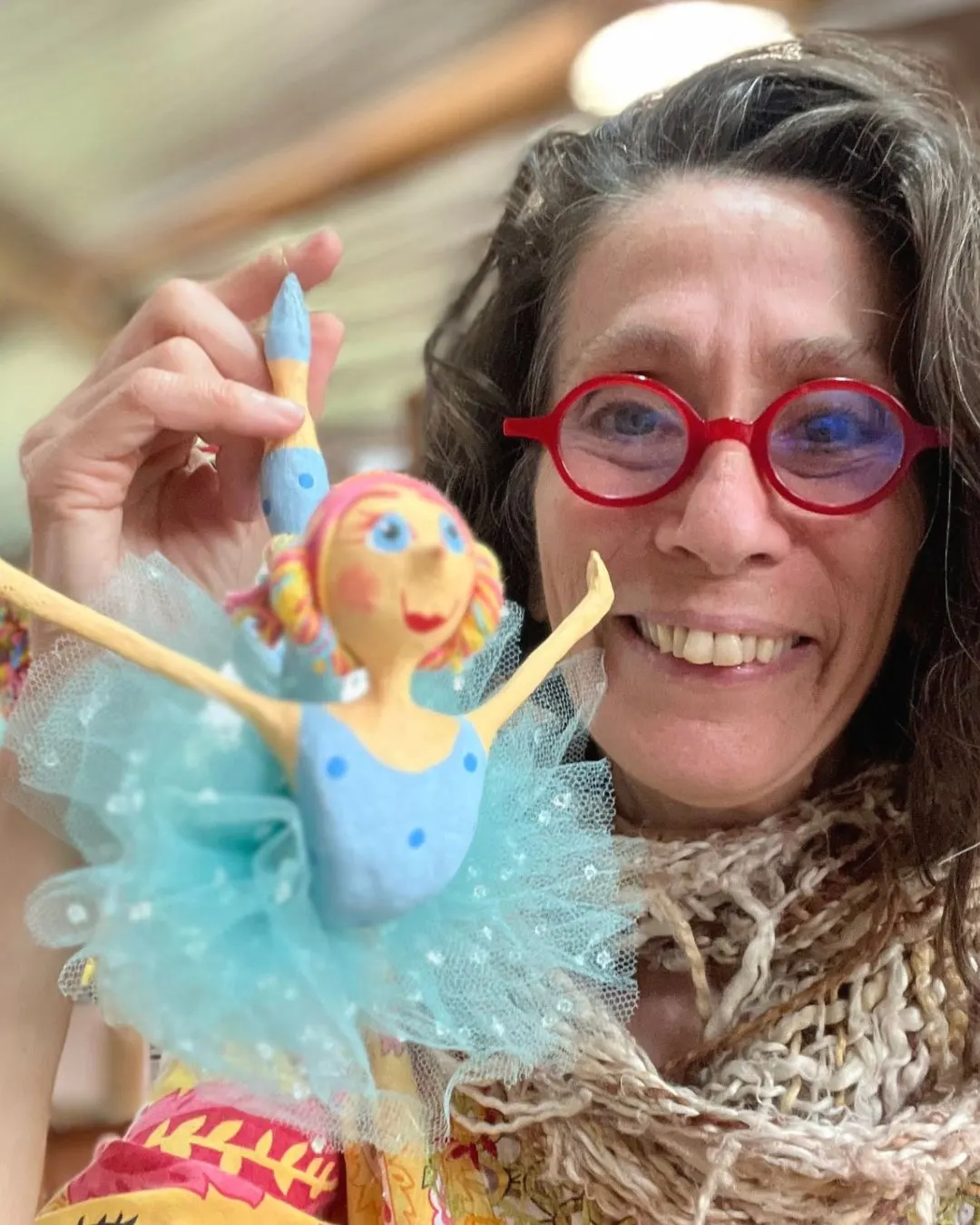 Dolores Montesó sorrindo com duas esculturas de papel machê